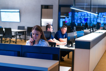 Technical Operator Works at Her Workstation with Multiple Displays while talking on the phone,...