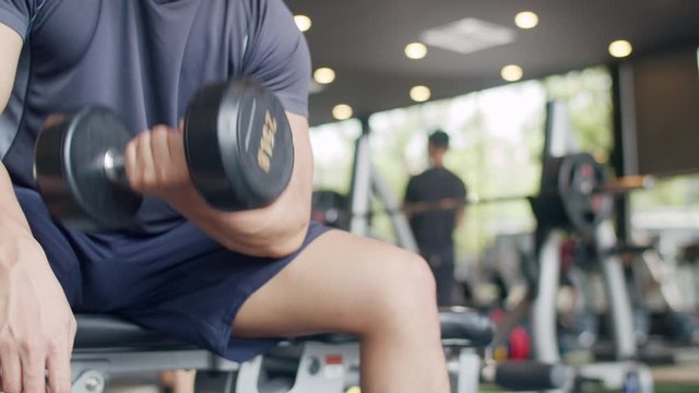 Young athlete Asian guy exercising doing lifting dumbbell fat burning workout in fitness class. Sportsman recreational activity, functional training, people working out, healthy lifestyle concept.