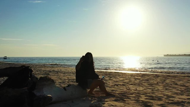 Bora Boro Island - A Lady Sitting At The Shore, Taking Photos Of The Beautiful And Bright Sunrise With A Cold Breeze Of The Ocean - Wide Shot