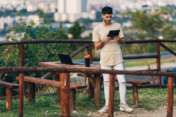 Creative man with digital tablet working at outdoors office in the hill