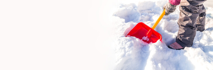 Child digs a snow shovel. Kid with his hands in mittens holds a red spade. Copy spase Banner