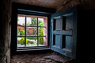 Fototapeta na wymiar Garden view through an old colonial style window with fence and shutter
