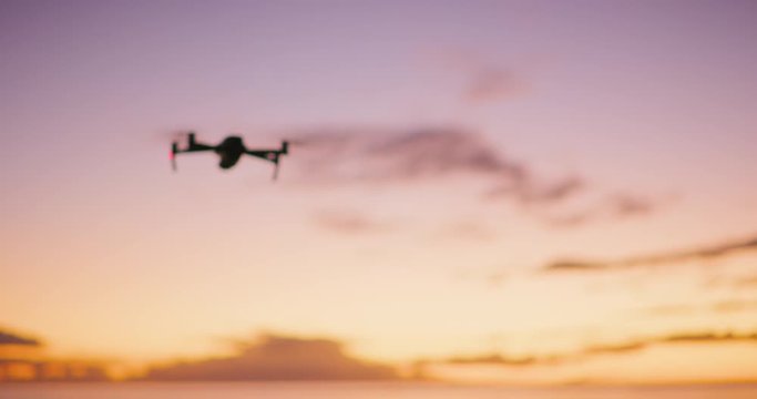 Silhouette of  UAV drone flying at sunset with a purple yellow sky