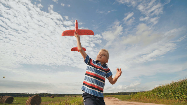 A little boy runs and launches a paralon toy airplane.