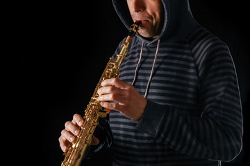 Naklejka premium soprano saxophone in the hands of a guy on a black background
