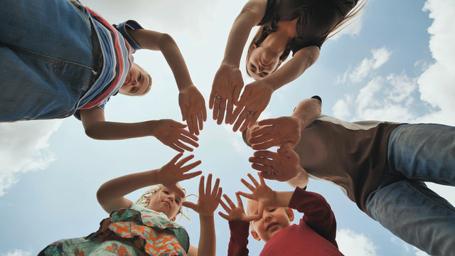 A young family of 6 connects the palms in a circle shape. The concept of a strong and friendly family.