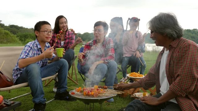 Happy asian family camping and enjoy with Bar-B-Q together at camping site.