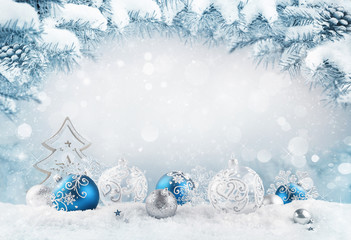 Merry Christmas background. Blue christmas balls and baubles and wooden decorative tree on the snow with fir branches. Mixed media.