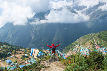 Tourist standing on the mountains edge and looking below to scenery view of Namche Bazaar the...