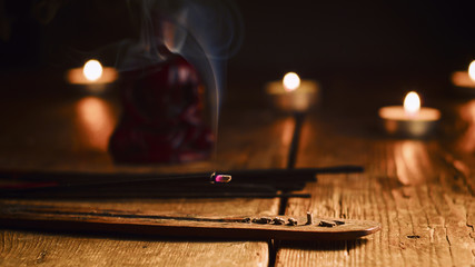 Burning incense stick. Buddha with incense sticks and candle on old wooden table.