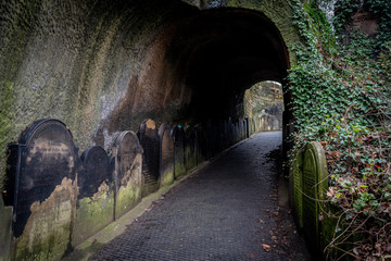 LIVERPOOL, ENGLAND, DECEMBER 27, 2018: Entrance to the creepy dark tunnel to the St James's Cemetery beside Liverpool Cathedral, with walls shaped by old moldy gravestones