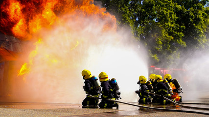 Group of firefighters fighting a fire and spraying high pressure water to fire