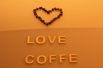 Coffee seeds heart and word love coffe orange background