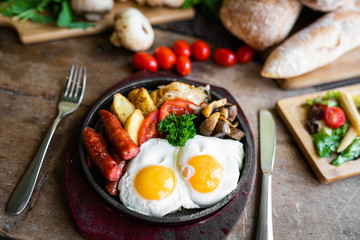 breakfast fried scrambled eggs with sausages and potatoes in a pan on a beautiful background