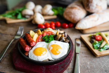 breakfast fried scrambled eggs with sausages and potatoes in a pan on a beautiful background