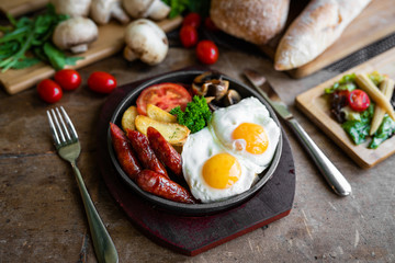 breakfast fried scrambled eggs with sausages and potatoes in a pan on a beautiful background