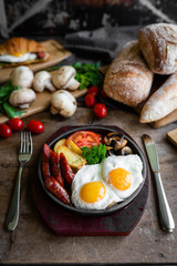 breakfast fried scrambled eggs with sausages and potatoes in a pan on a beautiful background