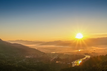 Naklejka na ściany i meble Mountain view misty morning above Kok river and Tha Ton City around with sea of mist and blue sky background, sunrise at Wat Tha Ton, Tha Ton District, Fang, Chiang Mai, northern of Thailand.