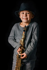 Naklejka premium happy child plays saxophone in studio