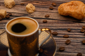 Coffee Cup, croissants, brown sugar and coffee beans on wooden background. Close up.