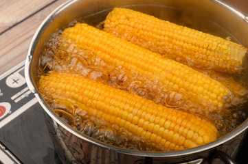 A few ears of corn are cooked in a saucepan. Healthy diet. Fitness diet. For a sweet treat. Close up.
