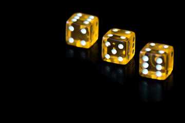 Several transparent yellow dice on a black surface close-up. Gambling сoncept background