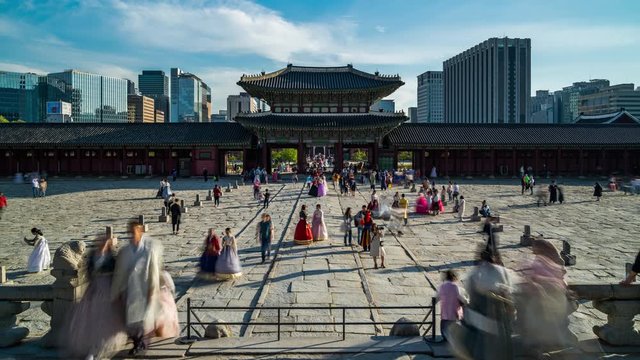 View of a the entrance of a korean palace in Seoul in late afternoon with tourists and city in background