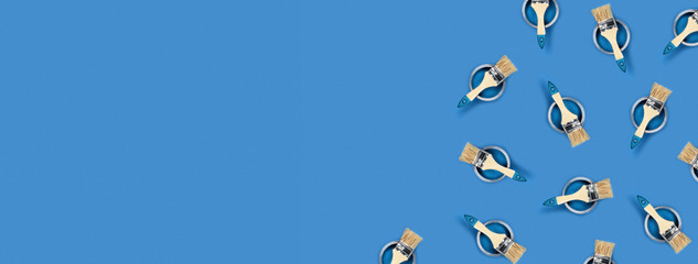 Renovation concept. Banner with blue background with color paint jars and brushes. Flat lay, top view, copy space.