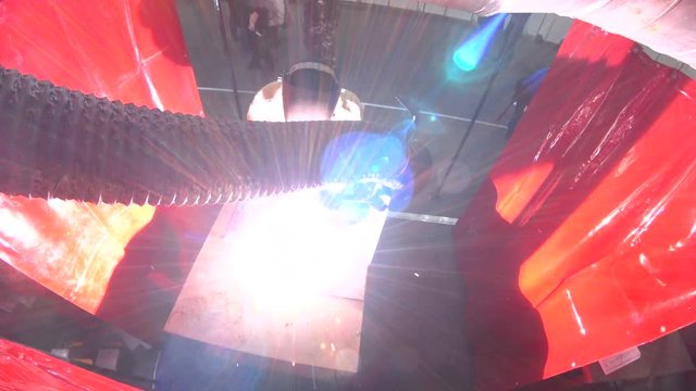 The welder initiates an arc by touching the metal table with an electrode. Air vent, workplace. View from above. Sparks, smoke, light artifacts.