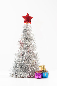 Silver coloured Christmas tree with a red star on top and isolated against a white background.