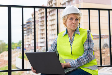 A female builder worker at a construction site works and controls the process.