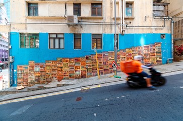 Naklejka premium A motorcycle courier passing by the famous Graham Street Wall Mural, a colorful street art and a popular Instagram check-in spot in Central District, Hong Kong, China, Asia