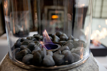 Bioethanol fueled portable fireplace burning at home, for live fire at home, no chimney and mantelpiece is needed. Liquid bio ethanol burns in cup. Round shaped glass with stones inside