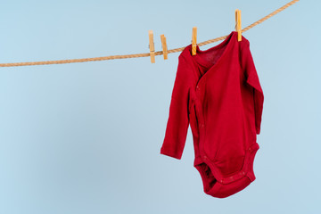 Baby girl clothes pinned on a clothesline against blue background