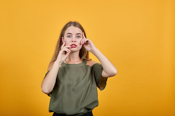 Young beautiful caucasian woman keeping hand on face, model gesture wearing haki shirt on isolated...