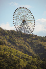 Fototapeta premium Ferris wheel in Tbilisi. Amusement park wheel on top of the hill rising above tbilisi, georgia