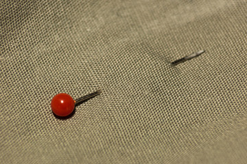 Pins with red balls stuck in a fabric