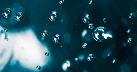 Bubbles of air on the smooth surface of blue water as an abstract background