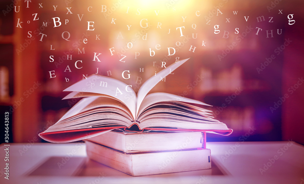 Poster imagine opening an old book blurred with magic power on the table and the english alphabet floating 