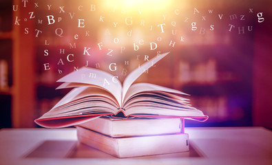 Imagine opening an old book blurred with magic power on the table and the English alphabet floating above the book with magic light as a beautiful background design.