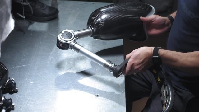 Production of a prosthetic leg. A man creates part of the leg. An engineer is testing the mechanical joint of a prosthetic leg. New sports body part.