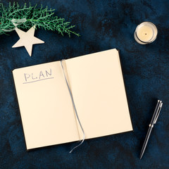 New Year resolutions or bucket list concept, a square flat lay mock-up with the handwritten word Plan, shot from the top on a dark background with a pen, a candle, and a star, with a place for text