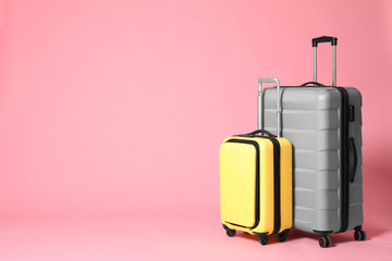 Stylish yellow and grey suitcases on pink background. Space for text