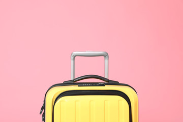Stylish yellow suitcase packed for travel on pink background