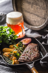 Beef flank steak in grill pan with batata puree garlic herb decoration and draft beer