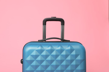 Stylish blue suitcase packed for travel on pink background