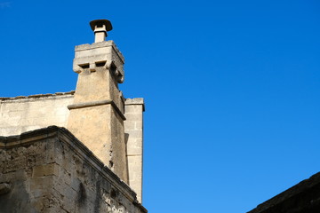 Chimney of an ancient Italian house in Matera. Above the old smokestack built with blocks of tuff stone, a fibrocemente (perhaps asbestos) fireplace has been installed.