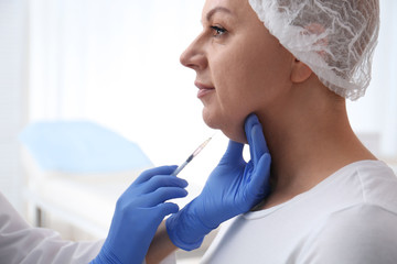 Mature woman with double chin receiving injection in clinic