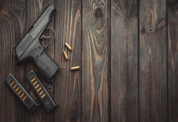 A modern black pistol and ammunition on dark wooden background. Weapons for police, army, special forces.
