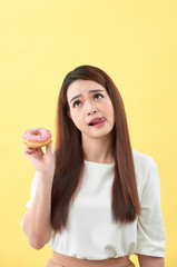 Close up portrait of a cute girl posing with donuts on yellow background